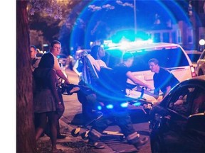 In this Sunday, July 6, 2014 photo, a man is wheeled on a stretcher after being shot in the leg on Chicago’s South Side. The Fourth of July weekend was a bloody one in Chicago, where at least nine people were shot to death and at least 60 others were wounded.