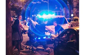 In this Sunday, July 6, 2014 photo, a man is wheeled on a stretcher after being shot in the leg on Chicago’s South Side. The Fourth of July weekend was a bloody one in Chicago, where at least nine people were shot to death and at least 60 others were wounded.