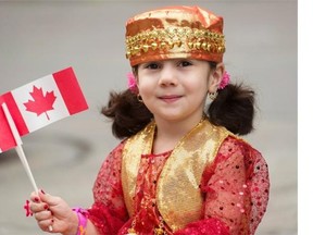 Three-year-old Zahar Murad waves flags as she watches the annual Canada Day parade in Montreal, Monday, July 1, 2013.