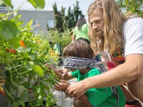Urban agriculture intern at Santropol Roulant Marc Antoine Fortin teaches a child to identify plants with touch during an urban agriculture workshop for children at the Santropol Roulant building in Montreal.