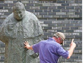 A worker installing the bronze statue of Pope John Paul II at St. Mary’s Cathedral gestures on July 24, 2014 in Hamburg.