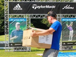 Worker Kristian Miller unloads boxes at a set-up by several manufacturers that make golf-related items at the The Royal Montreal Golf Club on Île-Bizard in the Montreal area, on Sunday, July 20, 2014 in preparation of the Canadian Open golf tournament is being held at The Royal Montreal Golf Club this week.