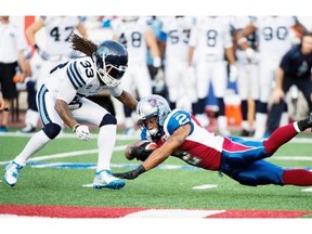 Alouettes’ Brandon Whitaker dives for extra yards as Argonauts’ Dwight Anderson moves in during first-half CFL football action in Montreal, Friday, August 1, 2014.