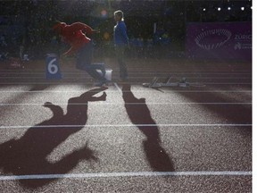 An athlete warms up (L) as an official looks on prior to the Men's 400m final during the European Athletics Championships at the Letzigrund stadium in Zurich on August 15, 2014.