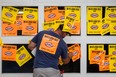 A protester supporting the firefighter's union places stickers on the garage door entrance to Montreal's city hall in protest of the proposed Bill 3, a pension reform bill, in Montreal on Monday, August 18, 2014. (Dario Ayala / THE GAZETTE)