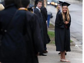 A University of Michigan graduate smiles at other students as they walk to the Michigan Stadium for the university's spring commencement in Ann Arbor, Mich. Saturday, May 3. (AP Photo/The Ann Arbor News, Brianne Bowen)