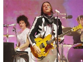 Win Butler of the Montreal band Arcade Fire plays guitar during the band’s concert at Parc Jean-Drapeau in Montreal on Saturday. Behind is drummer Jeremy Gara (right) and Régine Chassagne.