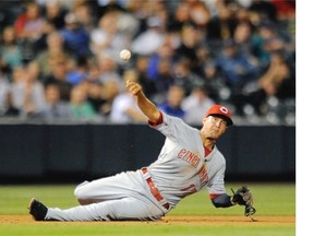 Cincinnati Reds third baseman Kris Negron throws to first base from the ground on a single by Colorado Rockies Nolan Arenado in the fifth inning of a baseball game on Thursday, Aug. 14, 2014, in Denver.