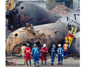 Cleanup crews take a break before removing one of the toppled rail cars in Lac-Mégantic July 19, 2013.