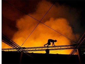 A man crawls on a truss of a building to witness a fire that engulfed a warehouse in Manila on August 26, 2014.