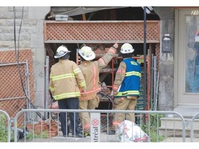 Firefighters examine a collapsed section of a building on Cartier St. near Ontario.