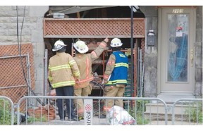 Firefighters examine a collapsed section of a building on Cartier St. near Ontario.