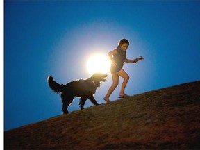 A girl plays with a dog as a perigee moon, also known as a supermoon, rises in Madrid, Sunday, Aug. 10, 2014.