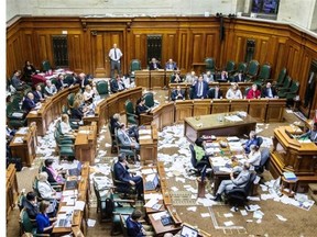 Montreal Mayor Denis Coderre speaks during a city council meeting in a room littered with papers after a protest by the firefighter’s union against the proposed Bill 3.