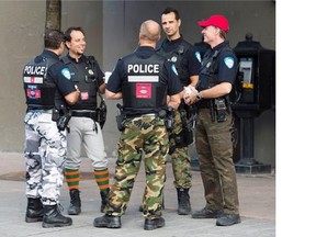 Montreal police officers are shown on a street in Montreal, Thursday, August 7, 2014. The funky pants and sticker-plastered city vehicles are just the beginning as workers and the province draw battle lines over a proposed reform of municipal pensions.