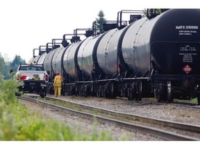 Transport Safety Board inspectors prepare to draw samples from a fuel tanker car involved in a Montreal, Maine and Atlantic Railway derailment that caused massive damage to the downtown core of Lac-Mégantic. The TSB inspectors are pictured in Nantes, on Wednesday July 17, 2013.
