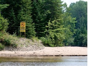 Signs prohibiting swimming are found on the banks of the Rivière Rouge in the Laurentians.