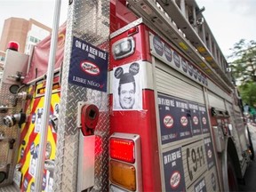 Posters of Montreal Mayor Denis Coderre wearing a Mickey Mouse hat placed on the door of a SIM firetruck in protest of the proposed Bill 3, a pension reform bill, as it's parked on Rene-Levesque boulevard in Montreal on Tuesday, August 5, 2014.