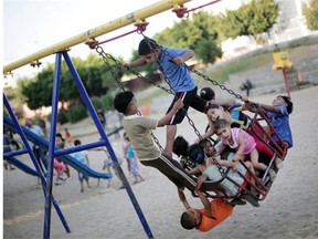 Palestinian children ride a swing in a public park during a temporary Hamas and Israel cease fire in Gaza City, Tuesday, Aug. 5, 2014.