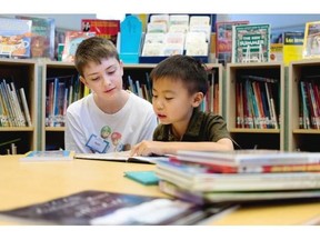Ryan Bujold, left, 13 years old, listens as Horace Chi, 8, reads as part of the reading buddies program at the Dorval Public Library. in Montreal on Friday July 11, 2014.