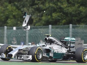 A pice of wing flys over Mercedes-AMG’s German driver Nico Rosberg after a collision with teammate Mercedes-AMG’s British driver Lewis Hamilton at the Spa-Francorchamps ciruit in Spa on Aug. 24, 2014 during the Belgium Formula One Grand Prix.