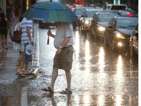 A man walks through a puddle as he crosses Peel street at Ste. Catherine street west as a summer rain storm drenches the downtown core in Montreal on Wednesday, July 17, 2013.