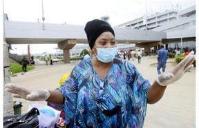 A woman, wearing a protective face mask and gloves, speaks to a worker upon arrival at the Murtala Muhammed Airport in Lagos on August 11, 2014. Nigeria confirmed a new case of Ebola in the financial capital Lagos, bringing the total number of people in the country with the virus to 10.