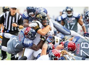 Alouettes Mike Edem and Kyries Hebert, rear, team up to stop Tiger Cats quarterback Jeremiah Masoli short of a first down Sunday at Molson Stadium.