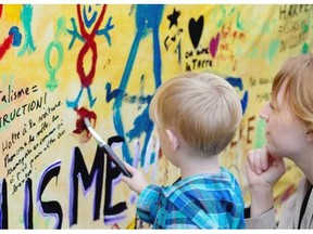 Andrea Davidge, right, watches as her son, Andrian Mackay, 3, add to a mural painted by climate activists to deliver to politicians as they take part in the People’s Climate March in Montreal on Sunday.