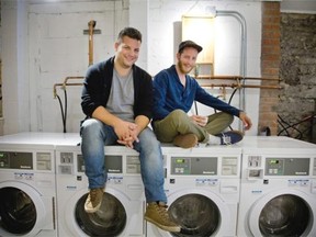 Chaz Desousa and Jesse Lewin sit atop washers in the Petit Bas Perdu laundromat that shares a space with Lewin’s café, L’Artiste Affamé, in Montreal, Tuesday September 9, 2014.