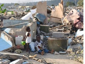 Children of a homeless family stand on the debris of destroyed houses in the Attecoube neighbourhood in Abidjan on September 20, 2014.