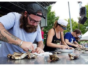 David Burnes, left, from Calgary and Ally Hogan of Montreal put their knifes to oyster during the shucking competition at the Montreal Oysterfest on Sunday Sept. 7, 2014.