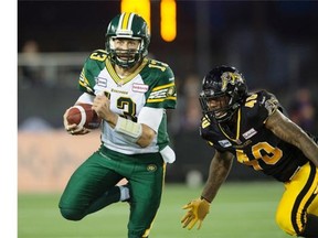 Edmonton Eskimos’ quarterback Mike Reilly, left, tries to avoid Hamilton Tiger-Cats’ Eric Norwood during first half CFL action in Hamilton, Ont., on Saturday.