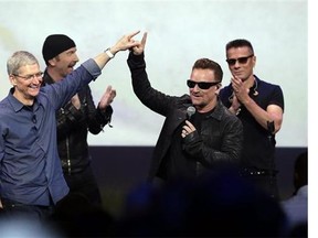 Apple CEO Tim Cook, left, greets Bono from the band U2 after they preformed at the end of the Apple event on Tuesday, Sept. 9, 2014, in Cupertino, Calif. Apple unveiled a new Apple Watch, the iPhone 6 and Apple Pay. (AP Photo/Marcio Jose Sanchez)