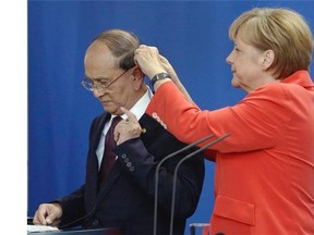 German Chancellor Angela Merkel, right, adjusts the translator headphone of the President of Myanmar, Thein Sein, during a joint press conference as part of a meeting at the chancellery in Berlin, Germany, Wednesday, Sept. 3, 2014.