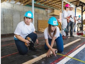 Habitat for Humanity volunteers Julie Philippon, left, and Jennyfay Berphiaume, right, work on placing the floor at a home in construction in St-Henri in Montreal on Tuesday, September 9, 2014.
