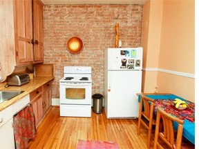 The kitchen in the apartment of artist Helga Schleeh’s has an exposed brick wall and hand-painted cabinets.