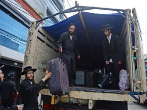 Members of an ultra-Orthodox Lev Tahor Jewish group unload their belongings from a truck as they arrive at the building where they will remain in Guatemala City on September 2, 2014. 230 ultra-Orthodox Lev Tahor Jews were expelled from the town of San Juan La Laguna by Mayan indigenous leaders.