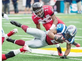 Montreal Alouettes’ Brandon Whitaker (2) dives for yardage as Calgary Stampeders’ Joshua Bell moves in for a tackle during during the first half at Molson Stadium in Montreal on Sunday, Sept. 21, 2014.