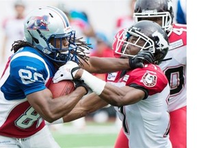 Montreal Alouettes’ James Rodgers, left, fights off a tackle by Calgary Stampeders’ Joshua Bell during during the first half at Molson Stadium in Montreal on Sunday, Sept. 21, 2014.