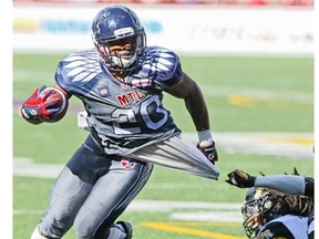 Montreal Alouettes’ Tyrell Sutton slips the grasp of  Hamilton Tiger Cats Ed Gainey during second half of Canadian Football League game in Montreal Sunday, Sept. 7, 2014.