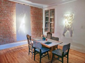 The dining room with exposed brick wall in artist Helga Schleeh's apartment in the Notre-Dame-de-Grace district of Montreal Tuesday September 02, 2014.  Her artwork includes a backlit human form sketch created by sanding paper instead of using a brush or pencil, left, and a backlit cast of a man's torso.