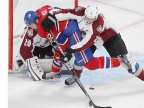 Montreal Canadiens Travis Moen, left, is checked by Colorado Avalanche defenceman Nick Holden in front of goalie Reto Berra during National Hockey League pre-season game in Montreal Thursday September 25, 2014.