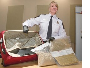 Candace Lyle, chief of operations for Canada Border Services (CBSA) at the Calgary airport, stands with a suitcase fitted with a false bottom where approximately 2.9 kg of suspected heroin was found in Calgary. Smugglers are hiding drugs in far more creative ways, but are still getting caught.