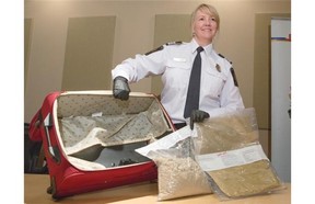 Candace Lyle, chief of operations for Canada Border Services (CBSA) at the Calgary airport, stands with a suitcase fitted with a false bottom where approximately 2.9 kg of suspected heroin was found in Calgary. Smugglers are hiding drugs in far more creative ways, but are still getting caught.