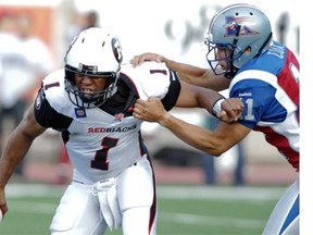 Ottawa Redblacks quarterback Henry Burris tries to fight off  Montreal Alouettes defender Chip Cox  in the first half of a pre-season CFL game at Molson stadium in  Montreal, on Friday, June 19, 2014.