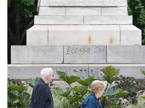 Pedestrians walk by pro-Scottish independence graffiti on Queen Victoria statue in Montreal, Wednesday, Sept. 17, 2014. The Scottish vote on independence takes place Sept. 18.