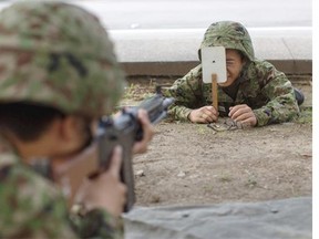 A student uses a postcard target to check the aim of a fellow student during rifle training at the Japan Ground Self-Defense Force (JGSDF) High Technical School on September 17, 2014 in Yokosuka, Japan. Each year, approximately 4500 students apply to enter the one and only high school run by JGSDF, and only 300 are accepted. The boys only school was opened in 1955 and caters to students between 15 and 19 years old across three grades. 90% of graduates continue on to careers in the JGSDF.