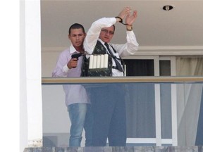 An unidentified man holding what appears to be a gun, parades a handcuffed hostage wearing what appears to be an explosive vest, on the 13th floor  balcony of the Saint Peter Hotel, in Brasilia, Brazil, Monday, Sept. 29, 2014. Firefighters and police have cordoned off the area and about 300 guests and other employees left the hotel, some reportedly told to leave by the same man carrying out the attack. Police didn't confirm whether there were actually explosives in the garment.