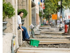 Waiter David Barros of Portus Calle restaurant takes a break along the torn up sidewalk of St-Laurent Blvd. in Montreal on Oct. 17, 2007. Lack of coordination led to work on the major artery taking much longer than intended, harming local businesses.